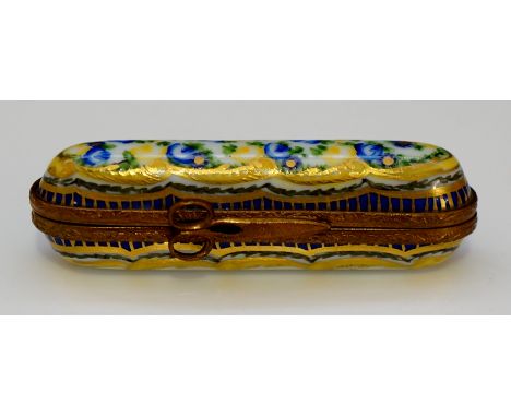 A brass mounted porcelain needle case with scissor clasp, the top decorated in yellow, blue and green with stylised flowerhea