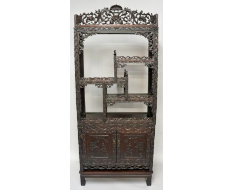 A good Chinese hardwood three piece display cabinet, the cornice finely carved with stylised shell, chrysanthemum blooms and 