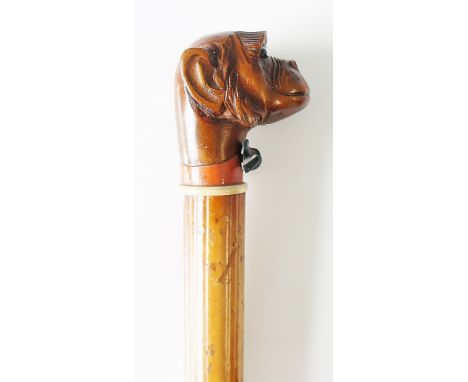 A 19th Century walking stick with carved chimp's head terminal, black bow tie, ivory collar, malacca shaft, no ferrule, 88cm 