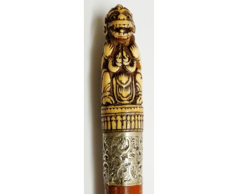 A 19th Century walking stick, the ivory terminal deeply carved as a seated monkey god figure, broad white coloured metal coll