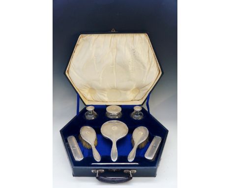 A silver dressing table set comprising: hand mirror, two hair brushes, two clothes brushes, three silver and cut glass dressi
