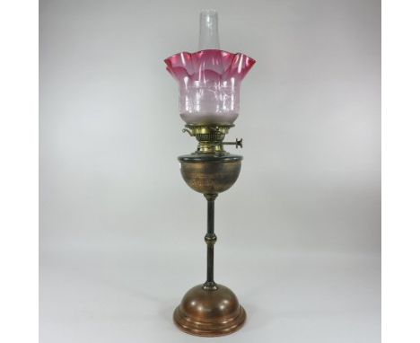 An Arts and Crafts copper oil lamp, by W. A. S. Benson, having a brass reservoir, on a knopped stem and domed base, with a Hi