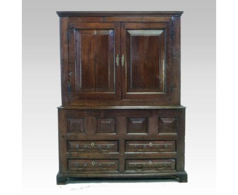 An 18th century Welsh oak press cupboard, having a moulded cornice, enclosed by a pair of panelled doors, with four short dra