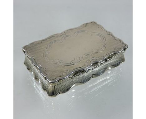 A Victorian silver snuff box, of rectangular shape, with engine turned decoration with a scrolled border, having a gilt inter