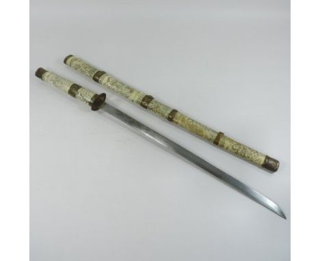 An early 20th century Japanese short sword, with a steel blade and carved bone and brass mounted handle and scabbard, decorat