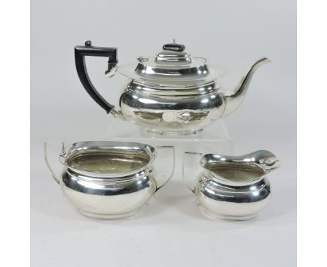 An early 20th century silver three piece tea service, of oval shape, comprising a teapot, with a hinged lid and ebonised hand