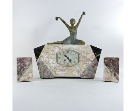 An Art Deco marble three piece clock garniture, of angular shape, surmounted by a painted spelter figure of a young seated la