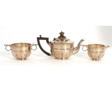 An Edwardian silver three piece tea service of circular form with reeded borders and raised strap work design to the body, co