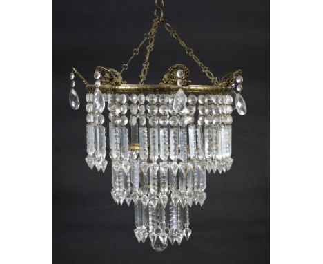 An early 20th century gilt-metal and brass three-tier chandelier with cut-glass lustre pendant drops. The circular upper gall