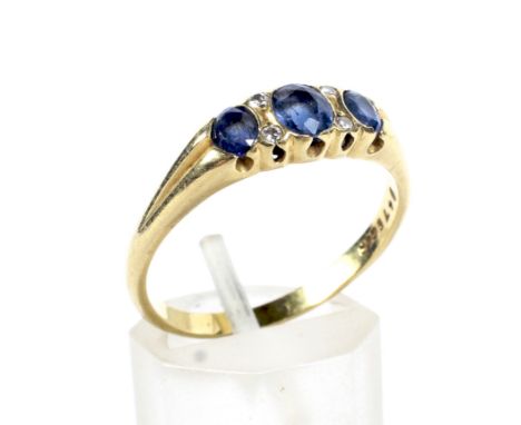 A vintage 18ct gold, sapphire and diamond dress ring. The three graduated oval mixed-cut sapphires spaced by pairs of small r