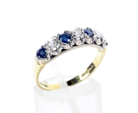 A vintage 18ct gold, sapphire and diamond seven stone ring. The four round mixed-cut sapphires spaced by smaller round brilli