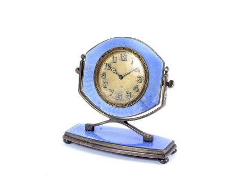 An Art Deco 8-day desk top silver and enamel mounted clock. With blue guilloche enamel mounts, the cream dial marked Swiss Ma