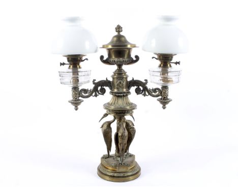 A Victorian brass and gilt-metal mounted twin light oil lamp. Centred with a gadrooned vase and cover issuing two leafy scrol