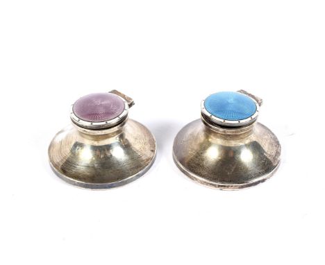 Two silver capstan-shaped and guilloche enamelled inkwells. With glass liners, the hinged covers with white enamelled borders