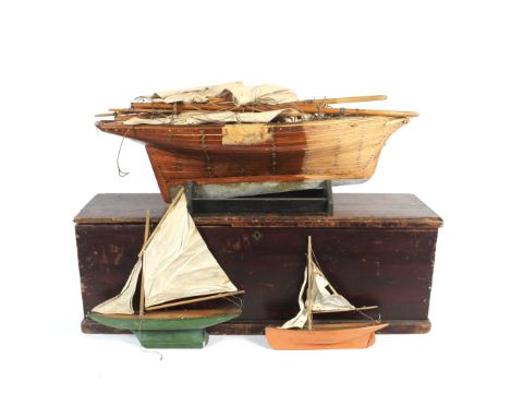 A large vintage wooden pond yacht and two smaller examples, boxed. With rigging and sails, all within a stained pine hinged b