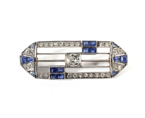 An Art Deco platinum, sapphire and diamond brooch. The canted-rectangular open panel grain-set at the centre with an early mo