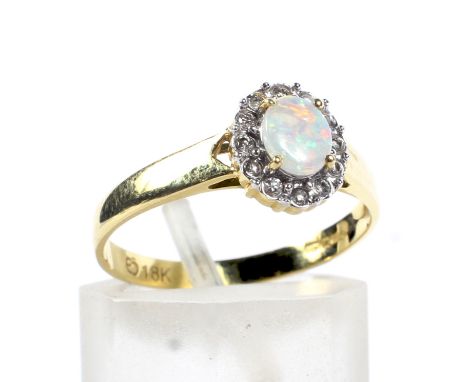 A modern 18ct gold, opal and diamond oval cluster ring. Centred with an oval cabochon white opal displaying a pleasing play o