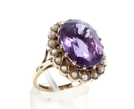A 9ct gold amethyst and half-pearl oval cluster ring. Centred with a large oval mixed-cut amethyst within a half-pearl 18 sto