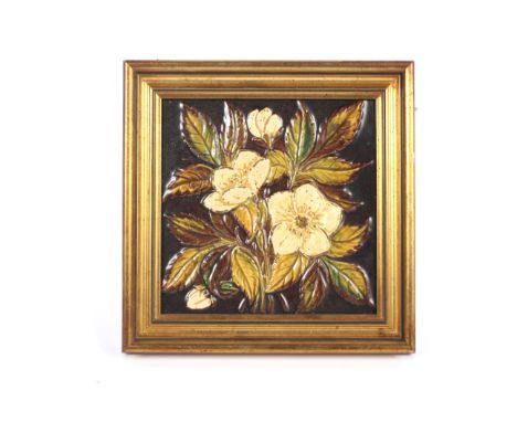 A framed Victorian relief-moulded glazed pottery tile. Decorated with a bouquet of white flowers and green leaves, reserved o