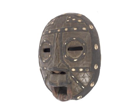 A vintage West African carved tribal mask inset with cowrie shells. With serpent carved nose and open mouth, 39cm high