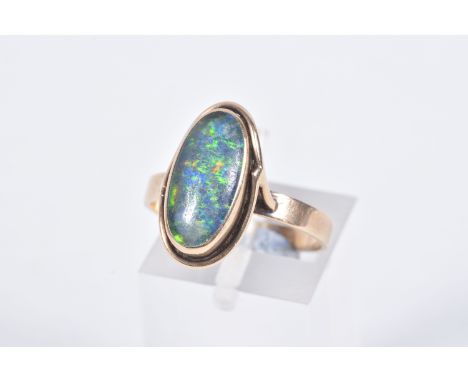 A YELLOW METAL OPAL TRIPLET RING, of an oval design, collet set opal triplet, to a scroll surround and polished band, stamped