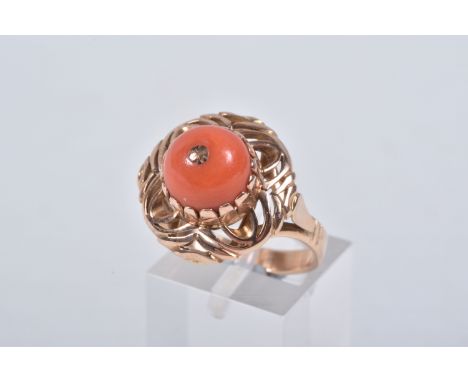 A YELLOW METAL CORAL RING, set with a raised coral cabochon with pin to the centre, in a claw setting to the open work circul