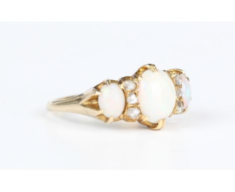 A gold, opal and diamond ring, circa 1910, claw set with three oval opals alternating with two rows of three rose cut diamond