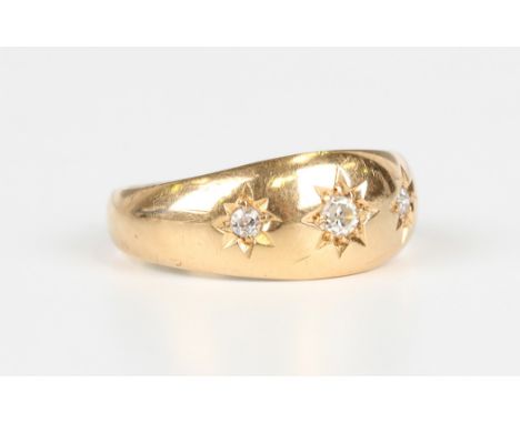 An 18ct gold and diamond three stone ring, star gypsy set with a row of cushion cut diamonds, inscribed within the band, Birm