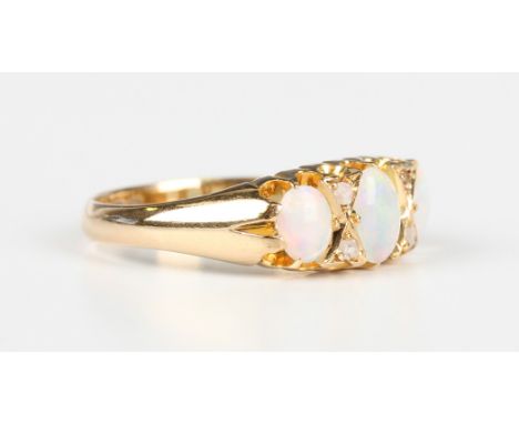 An Edwardian 18ct gold, opal and diamond ring, mounted with three oval opals and two pairs of rose cut diamonds at intervals,