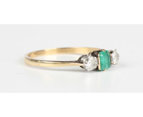 A gold, platinum, emerald and diamond three stone ring, mounted with a rectangular cut emerald between two cushion cut diamon