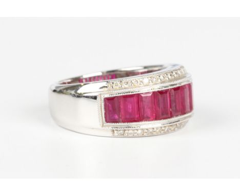 An 18ct white gold, ruby and diamond ring, channel set with a row of baguette cut rubies between circular cut diamond set sid