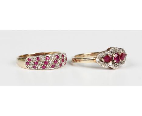 A 9ct gold ring, mounted with a central oval cut ruby between two pear shaped rubies within a surround of circular cut diamon