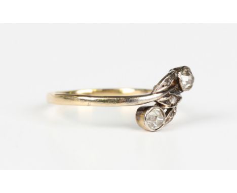 A gold and diamond ring in a twistover design, collet set with two principal cushion cut diamonds and three rose cut diamonds