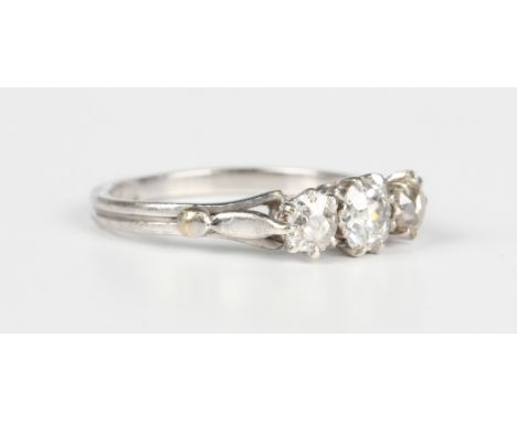 A diamond three stone diamond ring, claw set with a row of old mine cut diamonds, ring size approx O1/2, with a case and a Ge