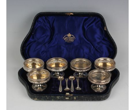 A set of six Victorian silver salts and four matching salt spoons, each salt of circular form with a shallow bowl decorated i