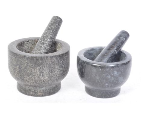 Two vintage 20th century granite stone pestle and mortars having a cylindrical pestle set with a circular mortar raised on a 