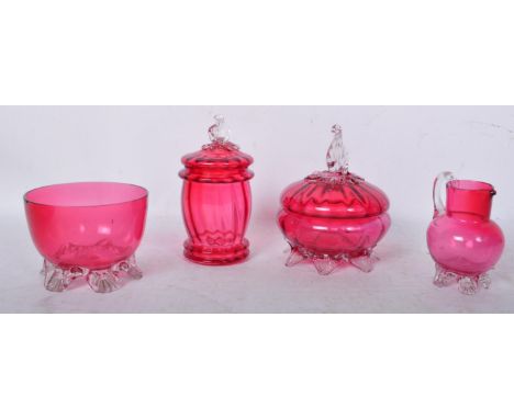 A collection of vintage 20th century cranberry glass pieces to include lidded vanity type pots, a jug and dish.