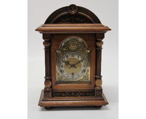 A late 19th century German mantle clock, the domed walnut case enclosing an eight day gong striking movement, faced by arched