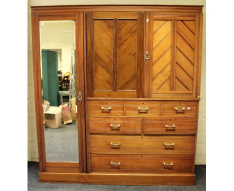 An edwardian walnut triple wardrobe press, the reeded, moulded cornice over a pair of doors enclosing trays, above five short