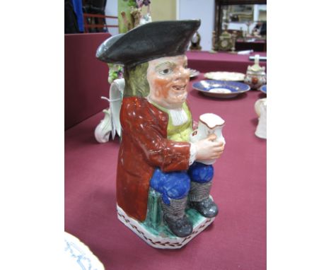 An Early XIX Century Pearlware Pottery Toby Jug, polychrome painted and modelled in traditional form as a seated toper, weari