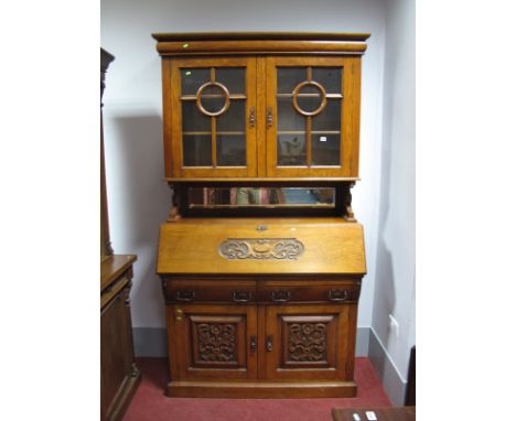 A Late XIX Century Oak Bureau Bookcase, with cushioned cornice above glazed astragal doors on shaped supports and mirrored sh