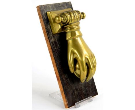 A VICTORIAN BRASS DOOR KNOCKER IN THE FORM OF A LADY'S HAND, 17CM H, MOUNTED ON AN OAK BOARD