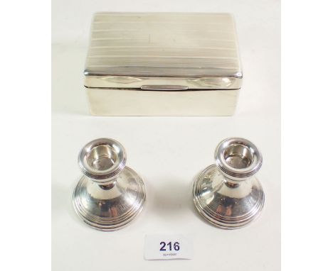 A silver cigarette box with flat line engine turned decoration together with a pair of squat silver candlesticks. 