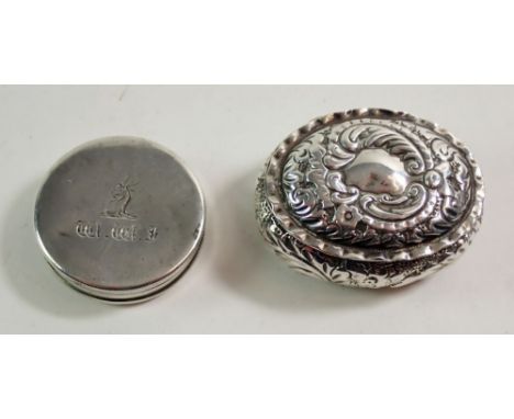 A silver oval trinket box, embossed scrollwork and a white metal circular pill or snuff box, 5 cm wide 