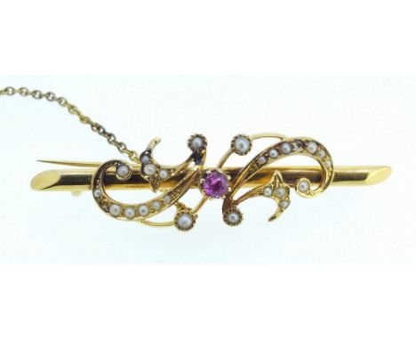 A Victorian 15 ct gold brooch set ruby within seed pearl set scrollwork, 4g with safety chain 