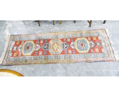 Eastern wool runner, with three central medallions on a red central field surround by a blue border with flowerhead decoratio