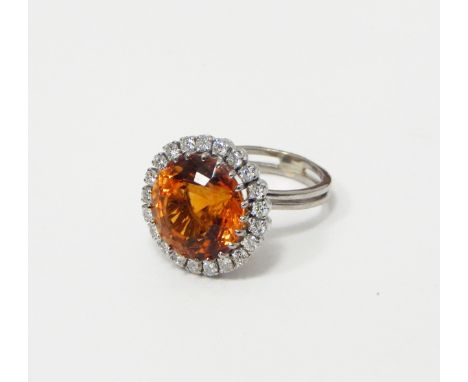 White metal diamond and citrine dress ring, the circular cut deep orange citrine surrounded by brilliant cut diamonds, unmark