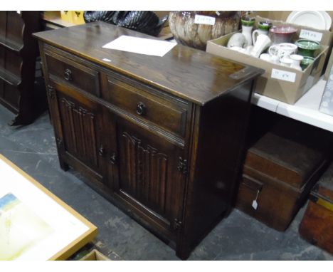 Oak reproduction dresser, the upper section having two plate racks, the cupboard base enclosed by linenfold panel doors, 107c