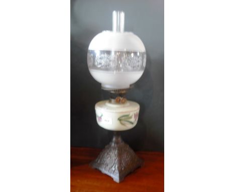 A late Victorian paraffin lamp, having a clear glass chimney, spherical shade above a florally decorated opaque glass reservo