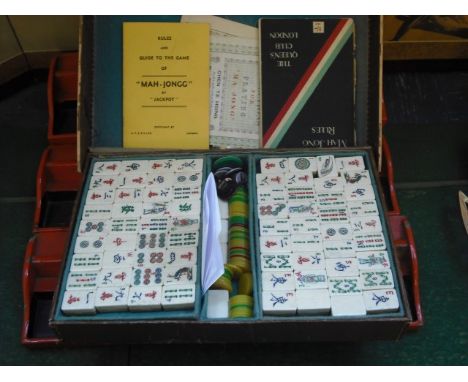 A mid-20th century Mah Jongg set with bone and bamboo tiles, other counters, rules and four red lacquer painted tile stands.